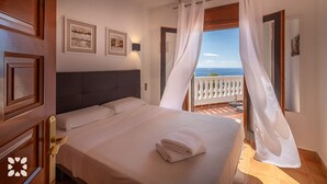 A hotel room with a bed, a view of the sea, and a balcony with white curtains. - Villa AGUILA by Abahana Villas (Benitachell)