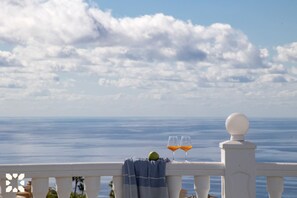 Ein Balkon mit Blick auf das Meer, zwei Gläser Orangensaft und ein Handtuch.
