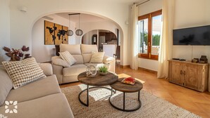 A living room with a sofa, coffee table, and TV. - Villa AGUILA by Abahana Villas (Benitachell)