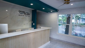 Eine Rezeption mit Marmorwand und einem Schild mit der Aufschrift 'Ivory Sands Beach Suites'.