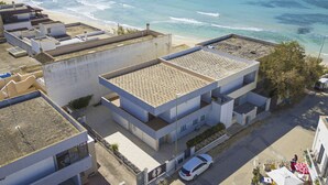 A coastal building with a flat roof, a car parked in front, and a view of the beach and ocean. - Torre Lapillo Apartment Sea View, 20m to Beach (Porto Cesareo)
