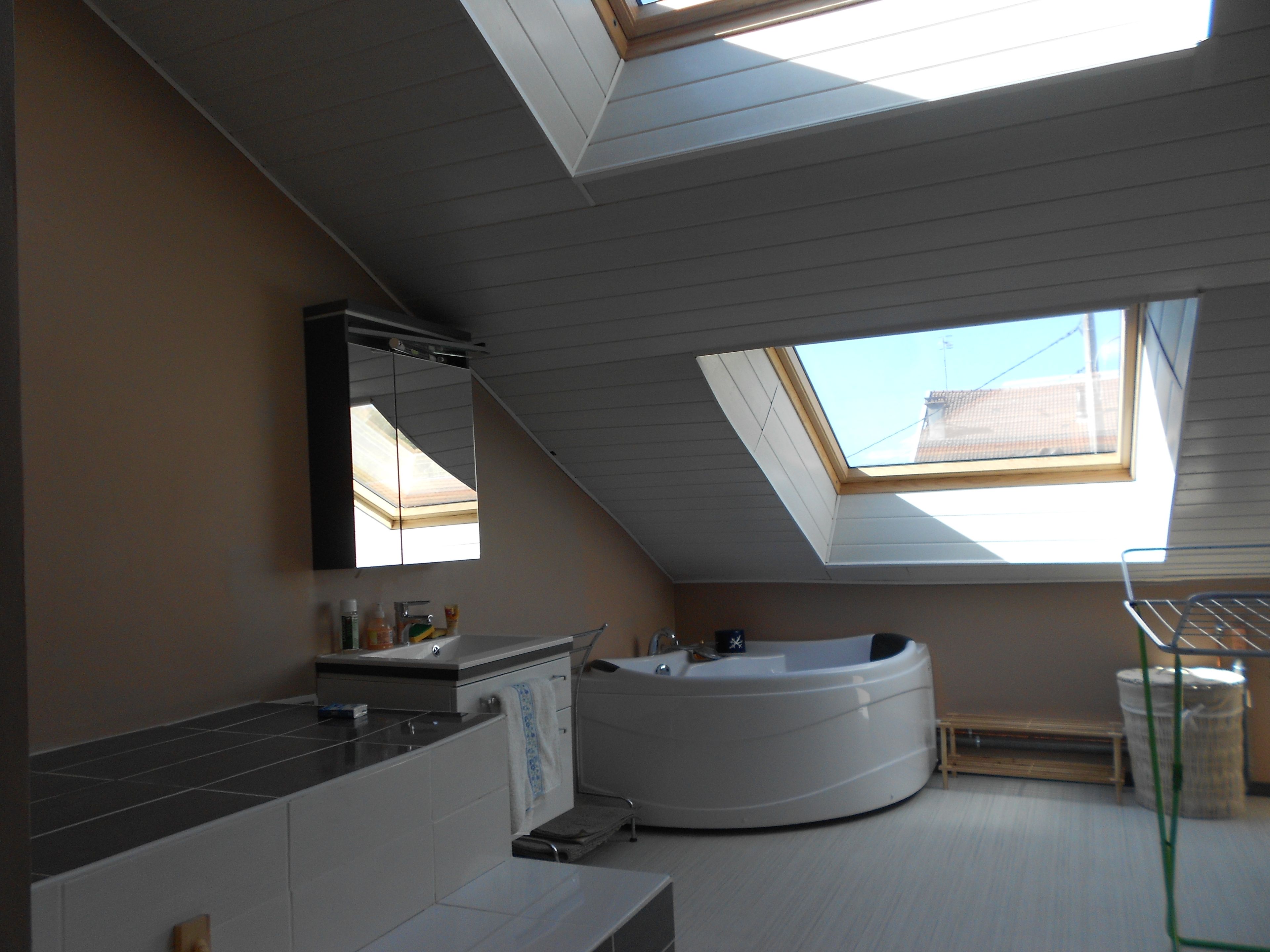 A modern bathroom with a skylight, a bathtub, and a vanity with a mirror.