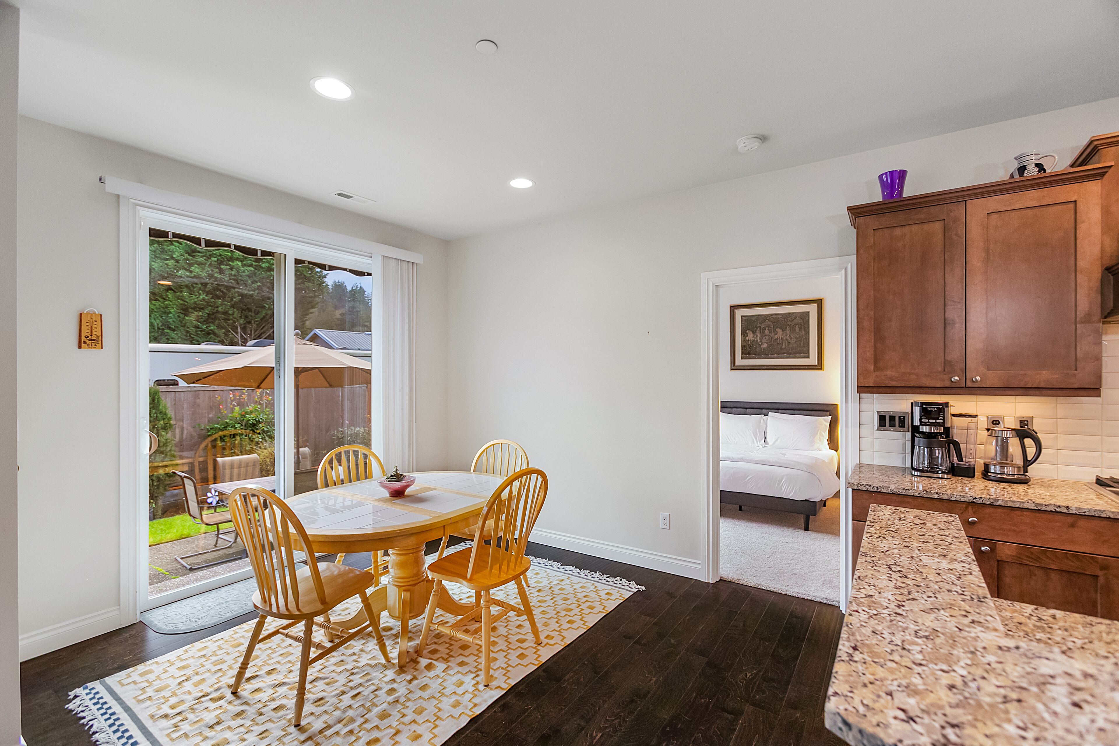 Una cocina moderna con encimera de granito, armarios de madera y un comedor con mesa y sillas.