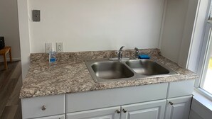 A kitchen with granite countertops, two stainless steel sinks, and white cabinetry. - Ocean view 2 bedroom apartment (Old Orchard Beach)