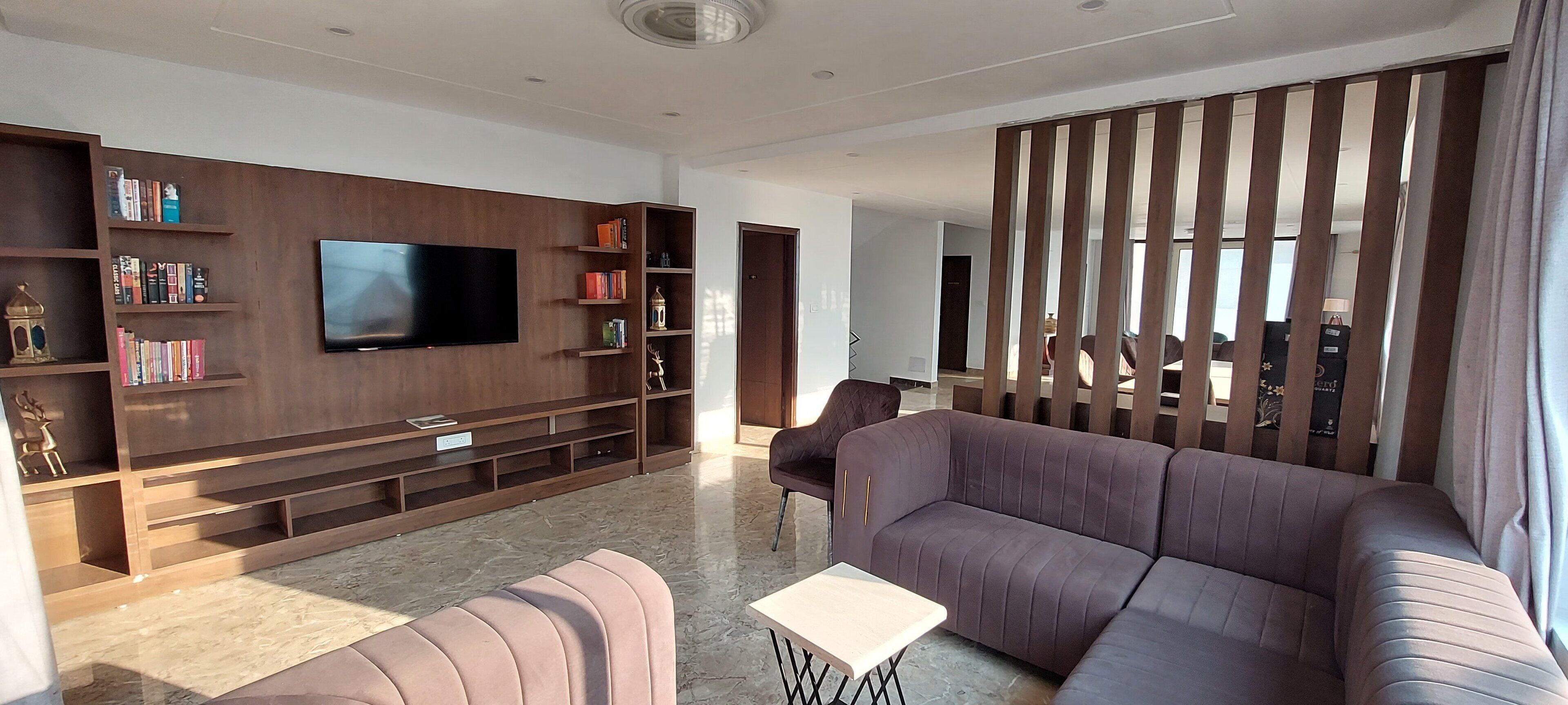 Un soggiorno moderno con una grande TV a schermo piatto, un divano, un tavolino da caffè e una libreria piena di libri.