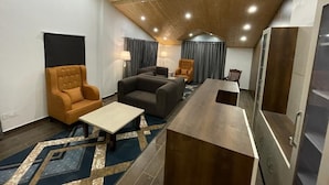 A modern living room with a wooden ceiling, a sofa, a coffee table, and a TV. - Apple Woods (Manali)