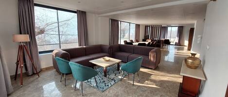 A modern living room with a sofa, two chairs, a coffee table, and a dining area in the background.