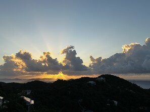 A coastal landscape with a sunset, houses on a hill, and a view of the sea. - Coral Sky Villa~4 BR 3.5 BA, private pool, ACs, generator, spectacular views (St John)