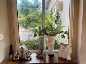 A window with a view of a garden, a decorative coral sculpture, and a framed welcome sign. - Coral Sky Villa~4 BR 3.5 BA, private pool, ACs, generator, spectacular views (St John)