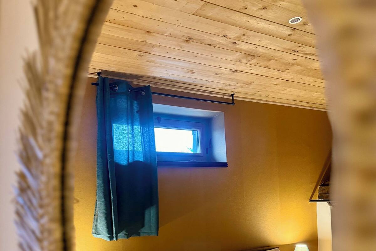 Ein Schlafzimmer mit Bett, Fenster und Nachttisch mit Lampe.