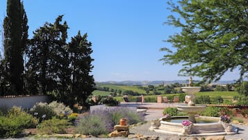 Un jardin agrémenté d’une fontaine, d’un espace aménagé pour s’asseoir et offrant une vue sur la campagne.