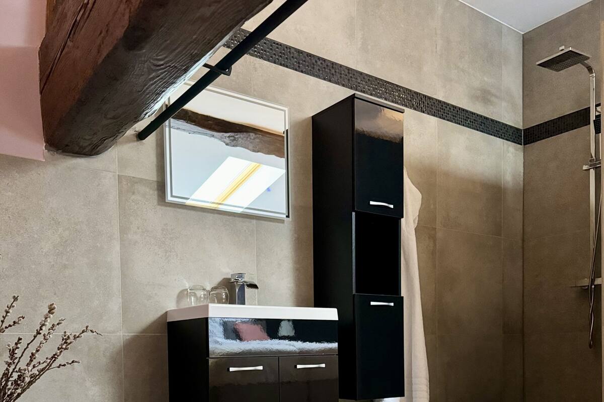 Ein modernes Badezimmer mit einer großen Badewanne, einem Spiegel über dem Waschbecken und einer Duschkabine.