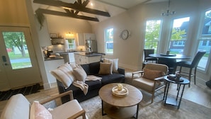 Uma sala de estar moderna com sofá, cadeiras, mesa de centro e área de jantar com mesa e cadeiras.