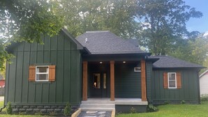 Uma casa térrea verde com um caminho de pedra que leva à porta da frente.