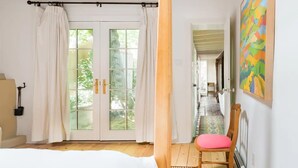 A bedroom with a large window, a bed, a chair, and a painting on the wall. - Canyon Road Hacienda in Heart of Santa Fe (Santa Fe)