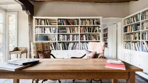 A study room with a wooden table, two chairs, and a bookshelf filled with books. - Canyon Road Hacienda in Heart of Santa Fe (Santa Fe)