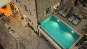 An aerial view of a building with a swimming pool, outdoor seating, and a stone facade. - Luxury Pool Villa Feliz (Dražin Vrt)