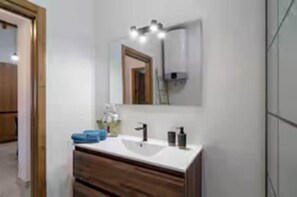 A bathroom with a white sink, wooden vanity, and a mirror with lights. - Casa Rural de Diseño (Alhaurín el Grande)