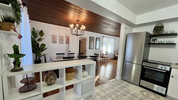 Eine moderne Küche mit Einbauofen und Kühlschrank, Holzboden und einer Essecke mit Stühlen und Tisch.