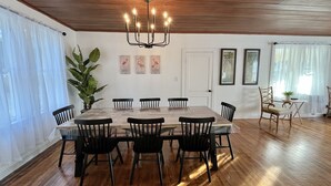 Ein Esszimmer mit Holztisch und -stühlen, einer Chandelüster und Bildern an den Wänden.
