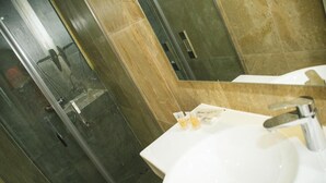 A bathroom with a white sink, a mirror, and a shower area with a glass door. - Oh Nice Revellin Ceuta (Ceuta)
