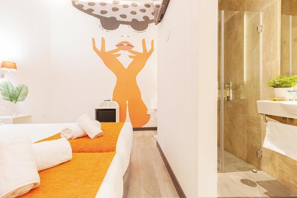 Una habitación de hotel con cama, zona de ducha y pared decorada con un gráfico.