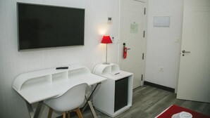 A modern room with a white desk, a chair, a red lamp, a blackboard, and a door with a fire alarm. - Oh Nice Revellin Ceuta (Ceuta)