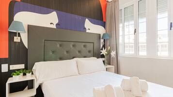 Ein Hotelzimmer mit einem großen Bett, zwei Nachttischen, einer Wandlampe und einem mit Vorhängen versehenen Fenster.