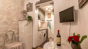 Cocina compacta con lavadora, zona de comedor con mesa de mármol y televisor montado en la pared.