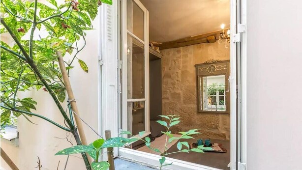 Una habitación con pared de piedra, un espejo y un ventanal pequeño.