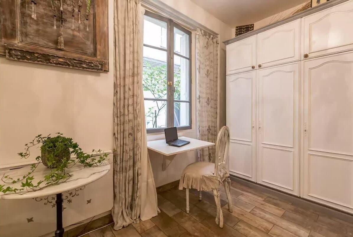 A room with a desk, chair, and wardrobe.