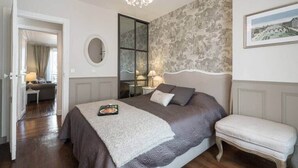 Ein Schlafzimmer mit einem großen Bett, einem Nachttisch, einem Spiegel und einer Chandelier.