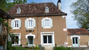 Ein zweigeschossiges Haus mit brauner Fassade, weißen Fensterläden und einem Ziegeldach.