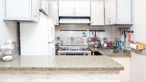 A kitchen with white cabinets, a gas stove, a sink, and various kitchen utensils. - The GEM View Boutique (Giza)