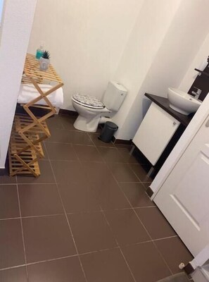 A compact bathroom with a toilet, sink, and drying rack.