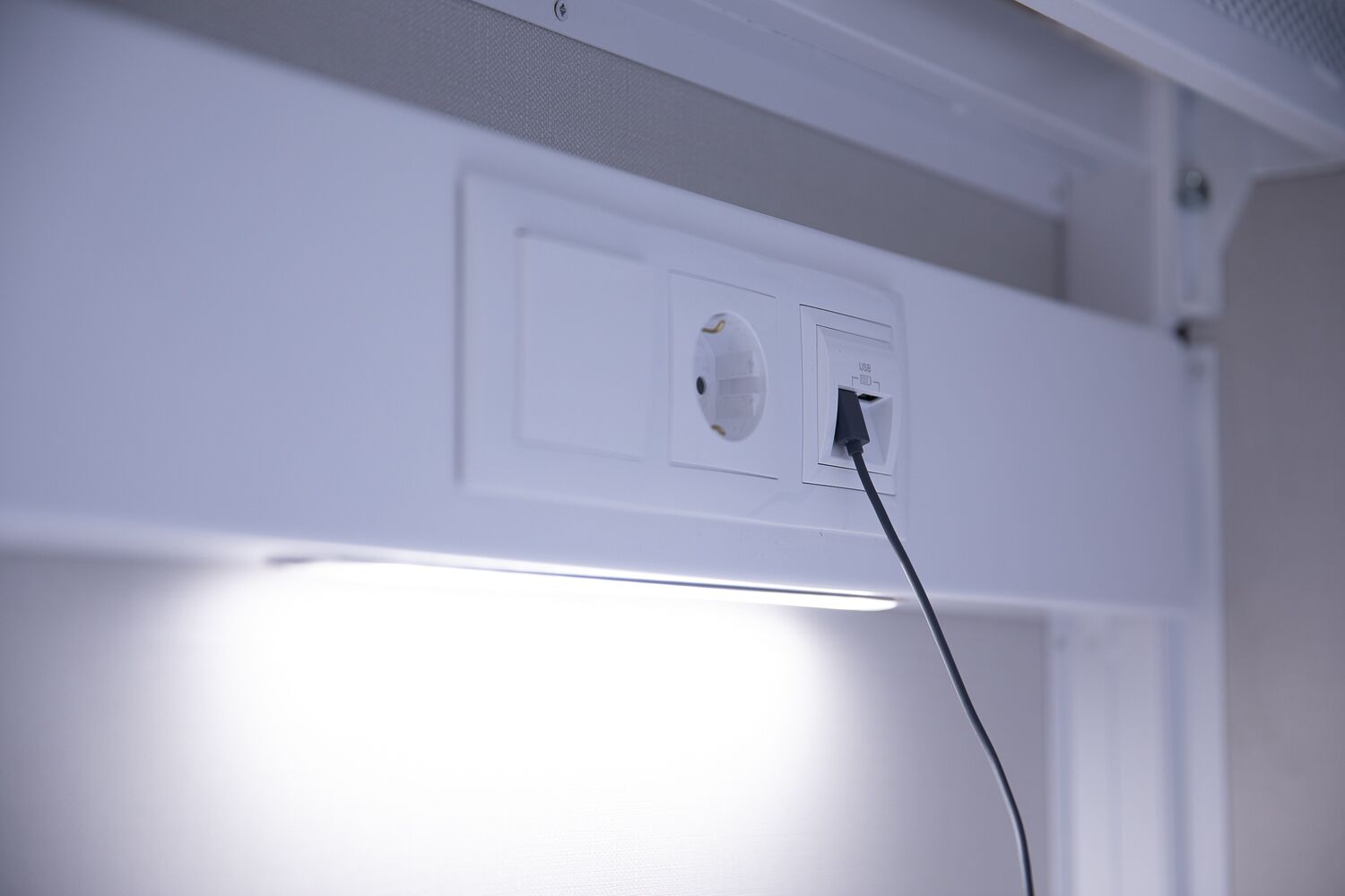 Een wandcontactdoos met een USB-poort en een stroomkabel aangesloten.