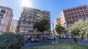 A multi-story building with balconies and a parking area in front. - National Square Napoli (Naples)