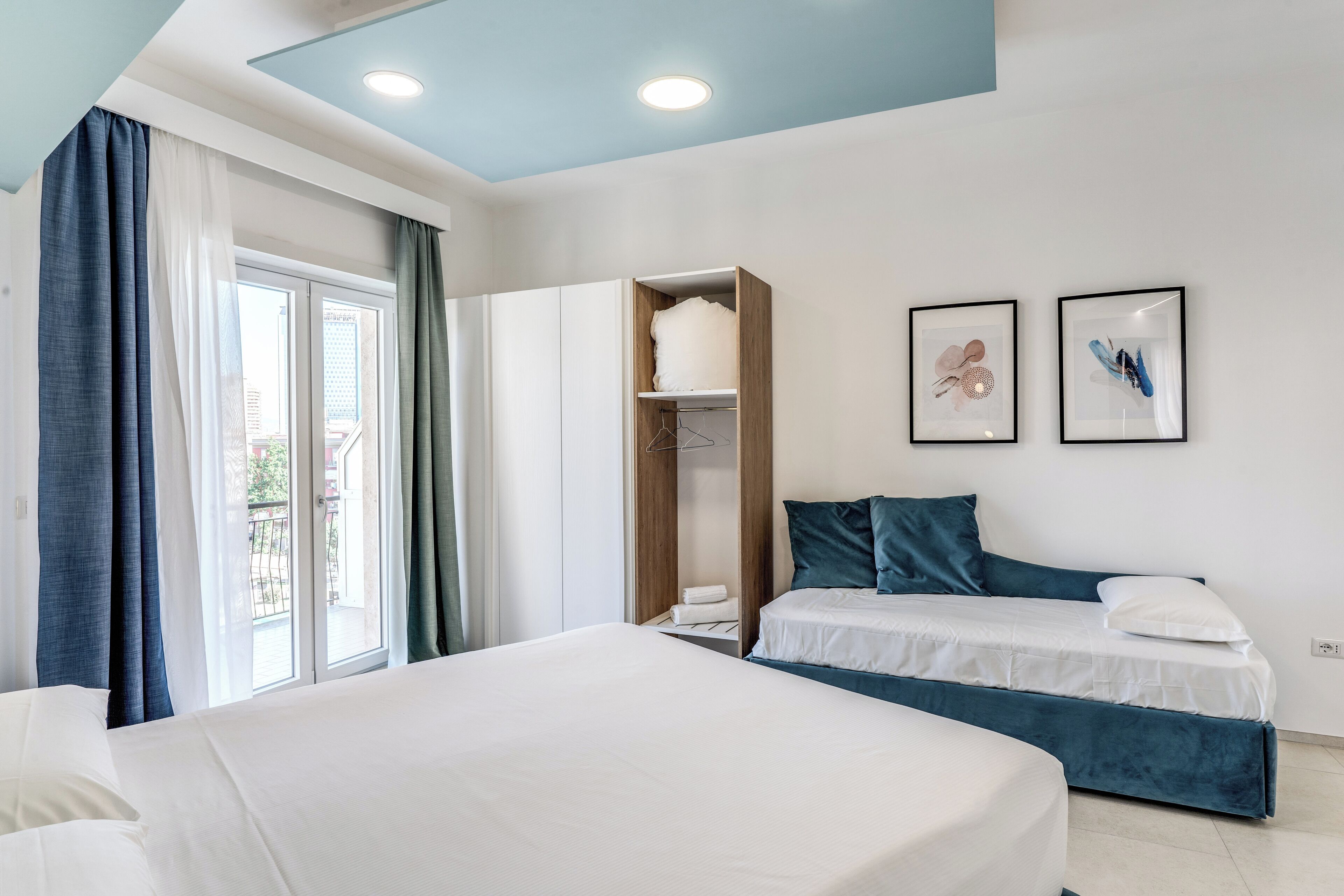 Une chambre d’hôtel avec un lit, une armoire et une fenêtre avec des rideaux.