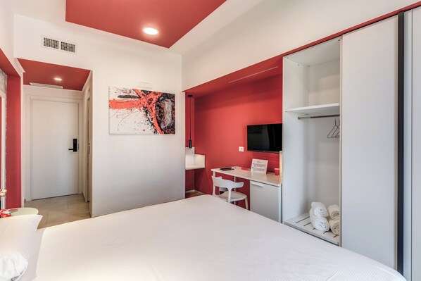 Une chambre d’hôtel moderne équipée d’un grand lit, d’un bureau avec une chaise, d’une armoire et d’un téléviseur.