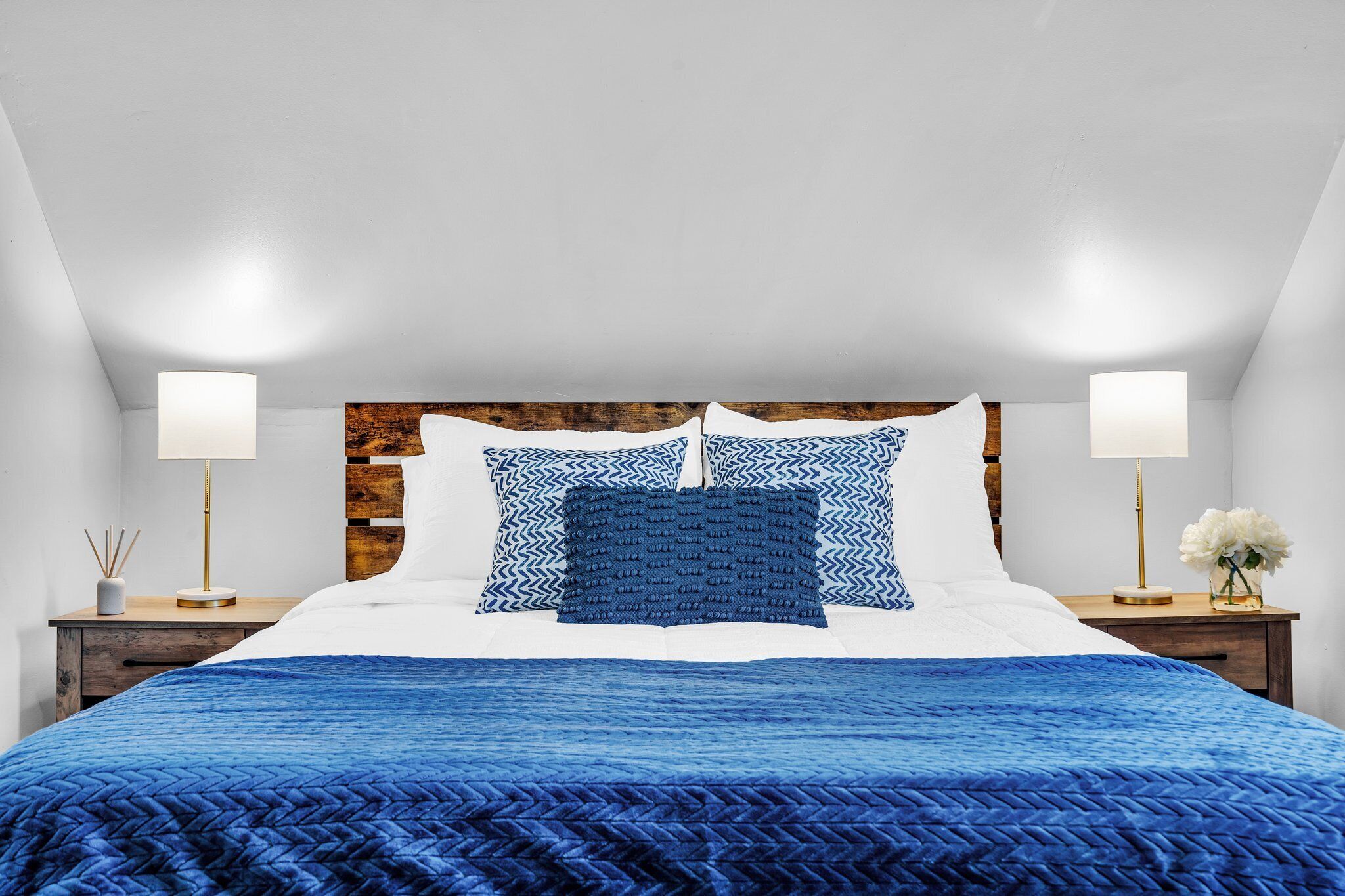 A bedroom with a bed, two bedside tables, and a wall with a wooden panel.