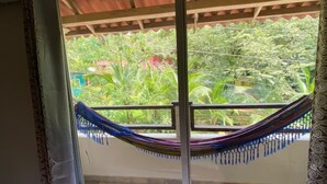 A room with a sliding glass door leading to a balcony with a hammock. - Hotel y Restaurante Mama Ines (Hicaco)