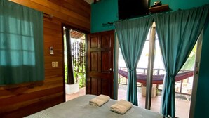 A room with a bed, wooden walls, a TV, and a view of the outdoors. - Hotel y Restaurante Mama Ines (Hicaco)
