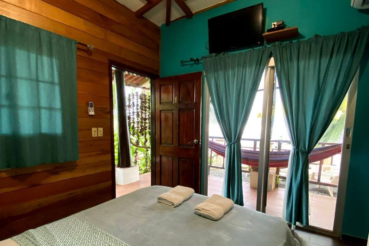 A room with a bed, wooden walls, a TV, and a view of the outdoors.