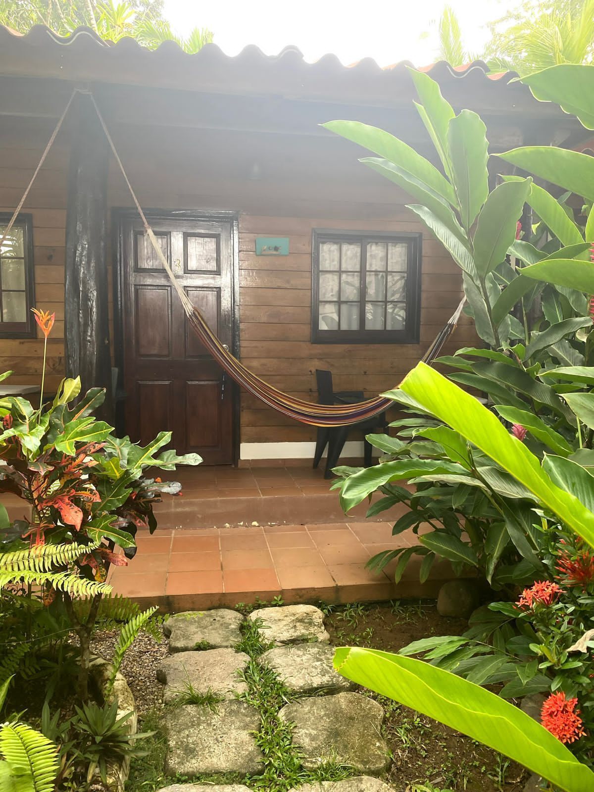 A wooden house with a hammock, a door, and a window.