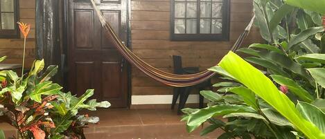 A wooden house with a hammock, a door, and a window.