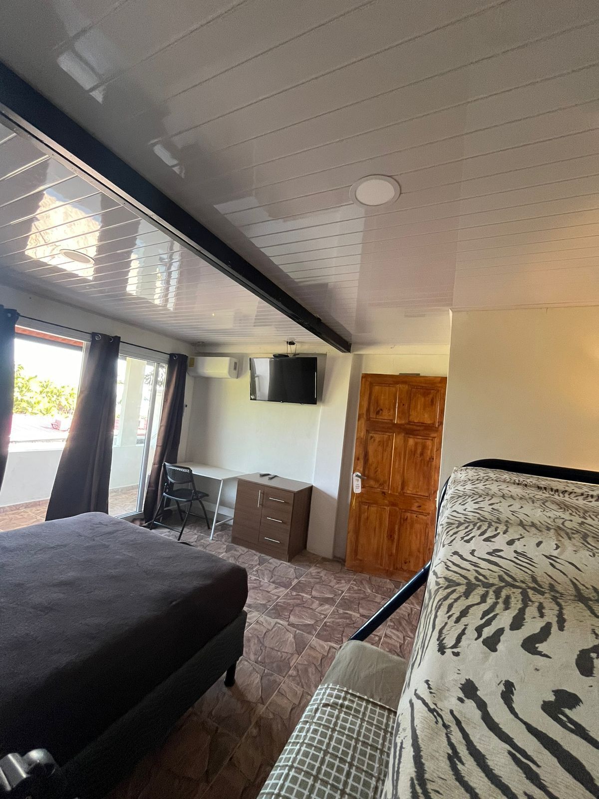 A bedroom with a bed, a desk, a chair, a TV, and a wardrobe.