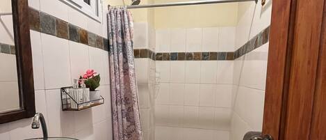 A small bathroom with a glass sink, white toilet, and shower area.