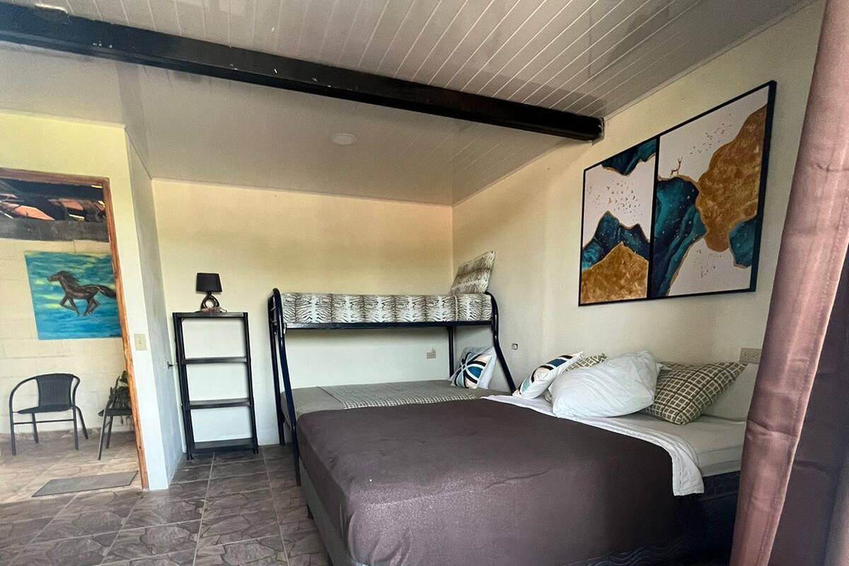 A bedroom with a bunk bed, a bedside table, a chair, and a painting on the wall.