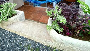 A wooden building with a stone facade, a hammock, and potted plants. - Hotel y Restaurante Mama Ines (Hicaco)