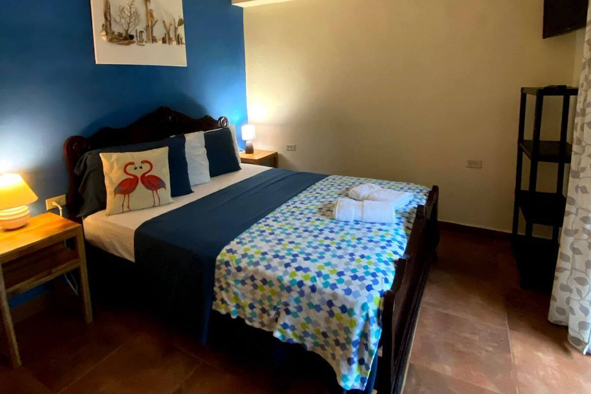A bedroom with a bed, nightstand, and a wall-mounted TV.